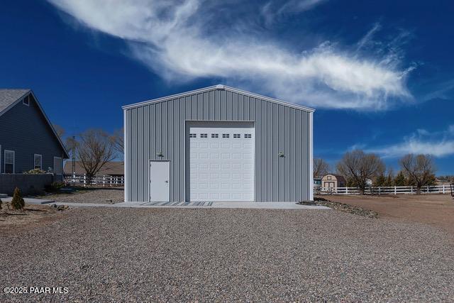 detached garage with gravel driveway and fence