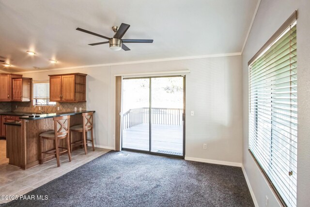 739 Yavapai Hills Dr, Prescott, AZ 86301 - kitchen featuring ornamental molding, dark countertops, a ceiling fan, brown cabinetry, and a kitchen bar