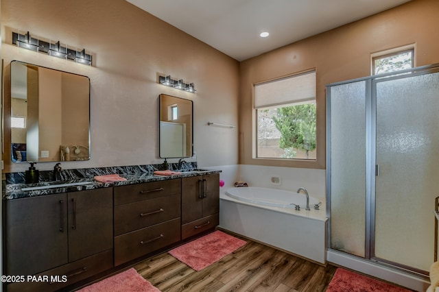 full bathroom with wood finished floors, a garden tub, a stall shower, double vanity, and recessed lighting