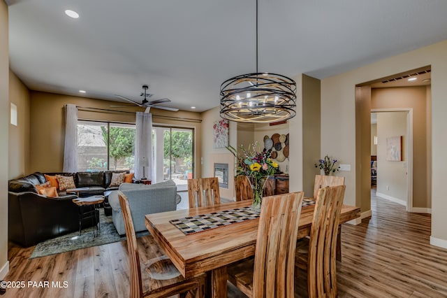 dining room featuring light wood-style floors, a ceiling fan, baseboards, a chandelier, and recessed lighting