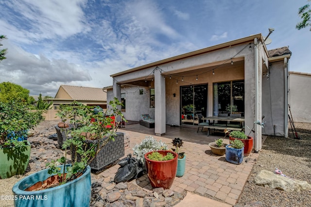 back of house with stucco siding, a patio area, and an outdoor living space