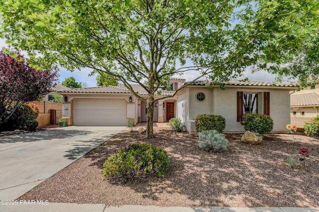 mediterranean / spanish-style house with stucco siding, concrete driveway, an attached garage, a tiled roof, and fence