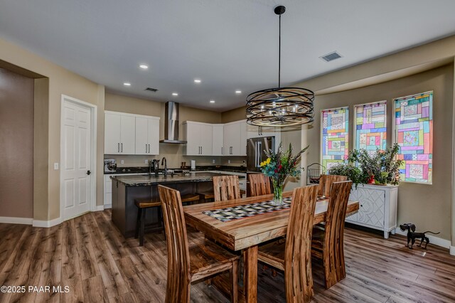 dining area with baseboards, wood finished floors, recessed lighting, and a chandelier