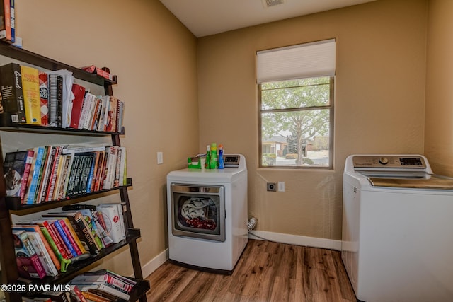 laundry area featuring wood finished floors, washing machine and dryer, and baseboards