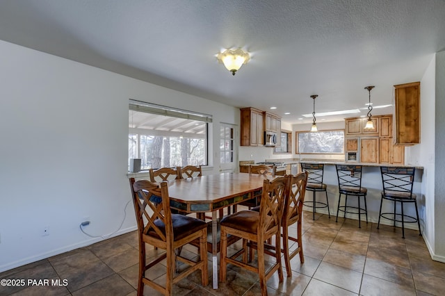 tiled dining area featuring baseboards and a textured ceiling