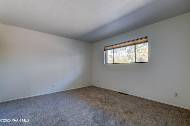 carpeted spare room featuring visible vents, a textured ceiling, and baseboards