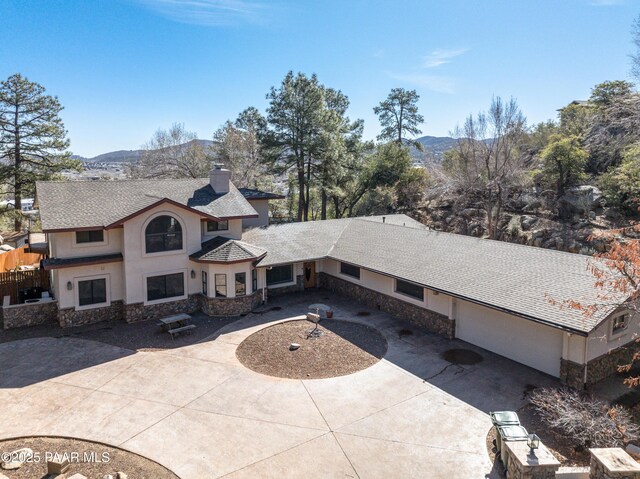 view of front of house featuring a chimney, stucco siding, a mountain view, stone siding, and driveway