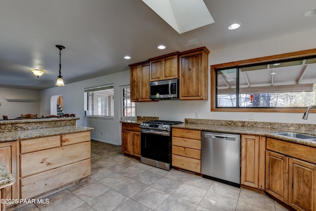 kitchen featuring pendant lighting, recessed lighting, appliances with stainless steel finishes, a sink, and light stone countertops