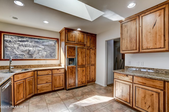 kitchen with recessed lighting, a skylight, a sink, stainless steel dishwasher, and brown cabinetry