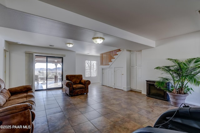 living room with stairs, a glass covered fireplace, tile patterned flooring, and visible vents