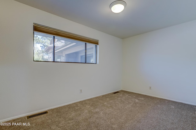 carpeted spare room featuring baseboards and visible vents