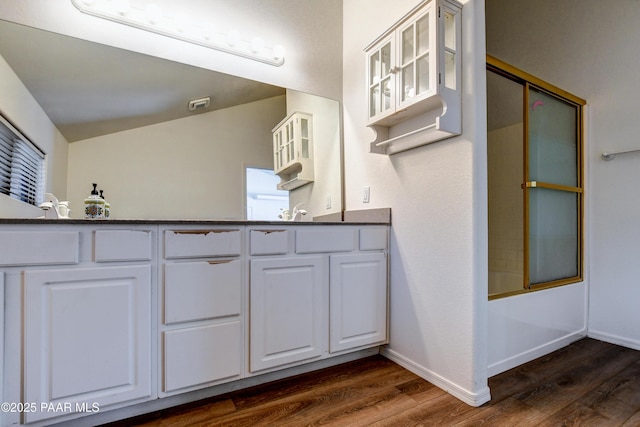 bathroom featuring lofted ceiling, baseboards, and wood finished floors