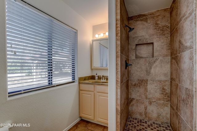 bathroom with a tile shower, vanity, and tile patterned floors