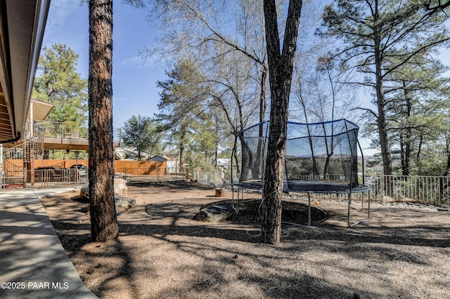 view of yard with a trampoline, a patio area, and fence