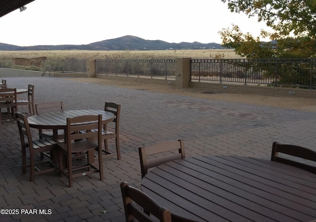 dock area featuring outdoor dining area, fence, a patio, and a mountain view