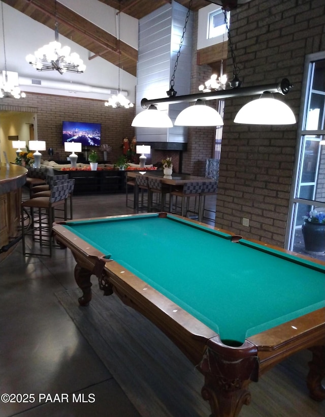 rec room with a chandelier, brick wall, a towering ceiling, finished concrete flooring, and a bar