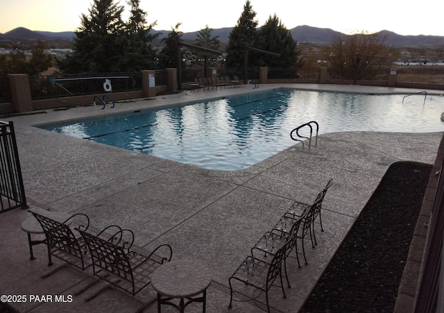 community pool with a patio, fence, and a mountain view