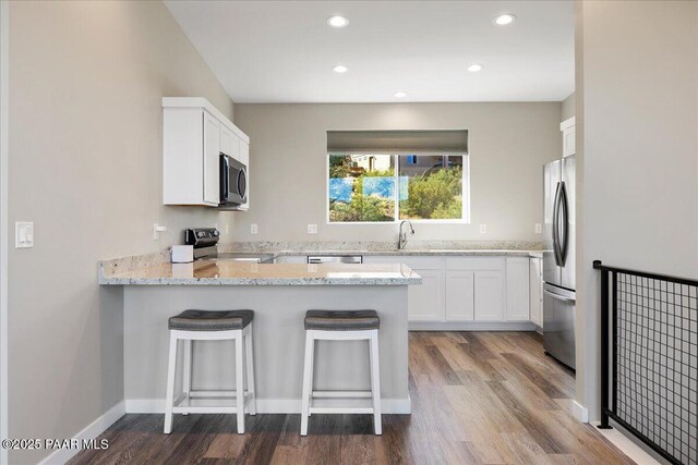 1841 N Jade Cir, Prescott, AZ 86301 - kitchen featuring stainless steel appliances, a peninsula, light stone counters, wood finished floors, and white cabinets