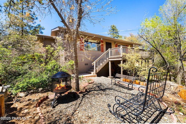 back of property featuring stairway, crawl space, a wooden deck, and an outdoor fire pit