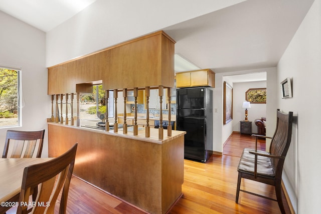 kitchen featuring freestanding refrigerator, light wood finished floors, a peninsula, and a healthy amount of sunlight