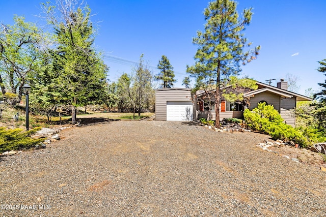 view of front of home featuring an attached garage, driveway, and a chimney