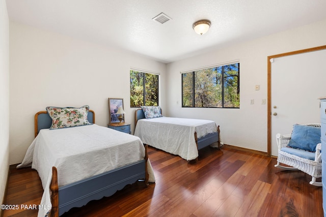 bedroom with baseboards, visible vents, and wood finished floors