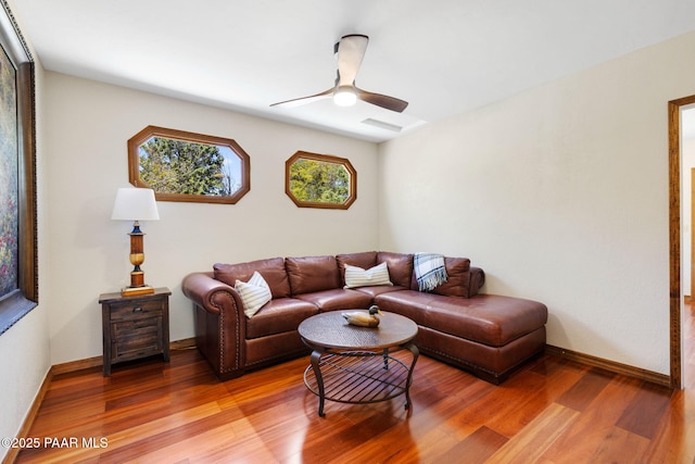 living room featuring baseboards, a ceiling fan, and light wood-style flooring