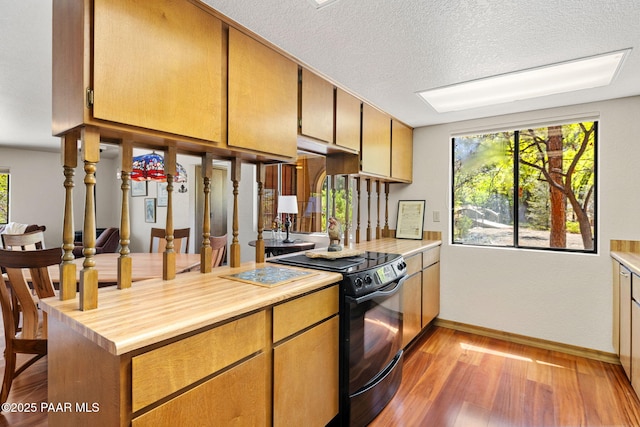 kitchen featuring light wood-style floors, a textured ceiling, black electric range oven, baseboards, and butcher block counters