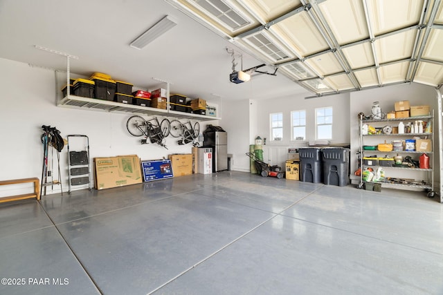 garage featuring freestanding refrigerator and a garage door opener