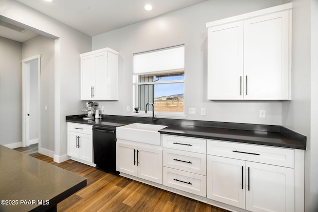 kitchen with dark wood-style flooring, dark countertops, white cabinetry, a sink, and dishwasher