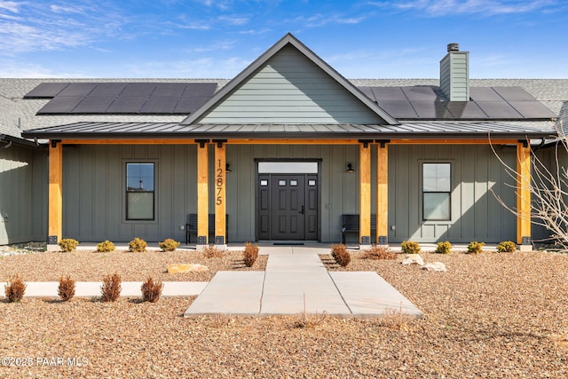 view of front facade with board and batten siding, covered porch, metal roof, and a standing seam roof