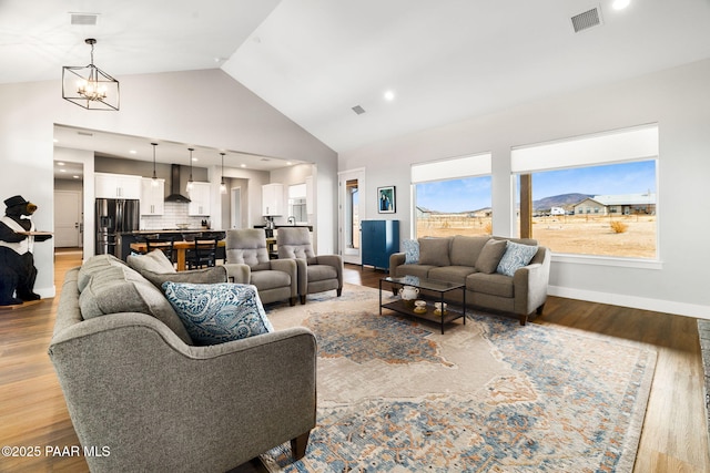 living room featuring light wood-style floors, visible vents, and high vaulted ceiling