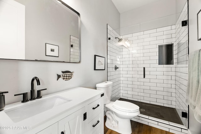 full bathroom with a stall shower, vanity, toilet, and wood finished floors