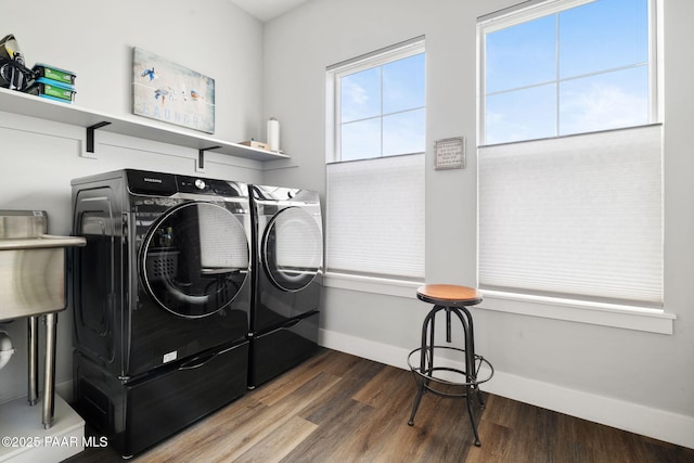 clothes washing area featuring washer and dryer, laundry area, baseboards, and wood finished floors