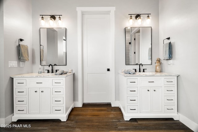 full bathroom featuring two vanities, a sink, and wood finished floors