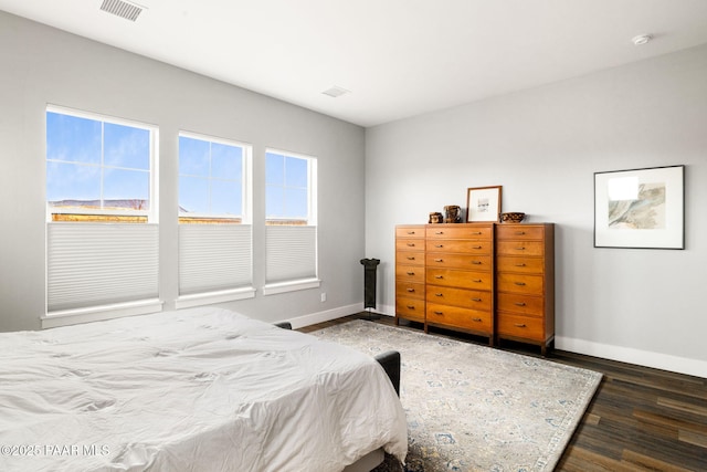 bedroom with visible vents, baseboards, and wood finished floors