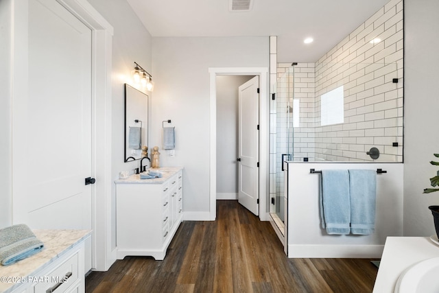 full bathroom featuring visible vents, a shower stall, vanity, wood finished floors, and baseboards