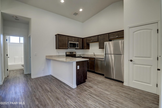 8346 Florentine Rd, Prescott Valley, AZ 86314 - kitchen featuring appliances with stainless steel finishes, dark brown cabinets, wood finished floors, a peninsula, and high vaulted ceiling