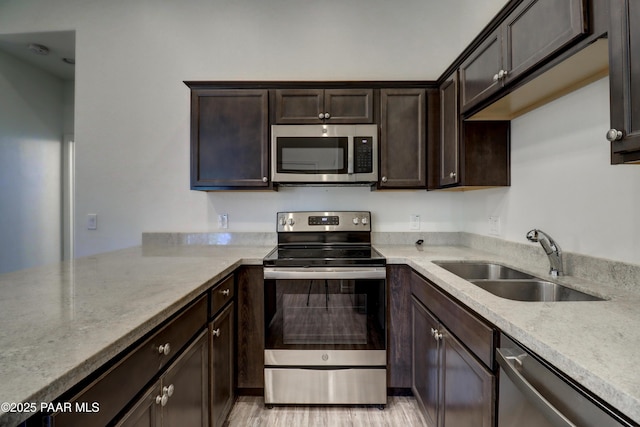 8346 Florentine Rd, Prescott Valley, AZ 86314 - kitchen with appliances with stainless steel finishes, dark brown cabinets, a peninsula, light stone countertops, and light wood-type flooring