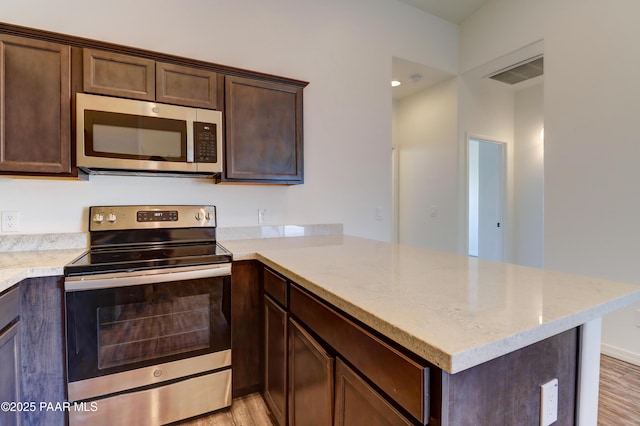 8346 Florentine Rd, Prescott Valley, AZ 86314 - kitchen featuring stainless steel appliances, a peninsula, light wood-style floors, and dark brown cabinetry