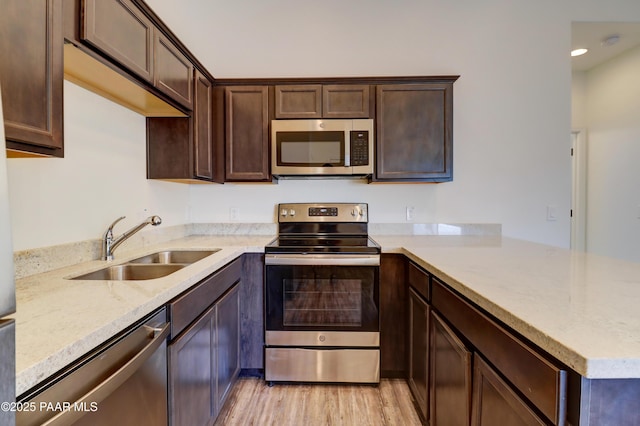 8346 Florentine Rd, Prescott Valley, AZ 86314 - kitchen with appliances with stainless steel finishes, a peninsula, light wood-type flooring, dark brown cabinets, and recessed lighting