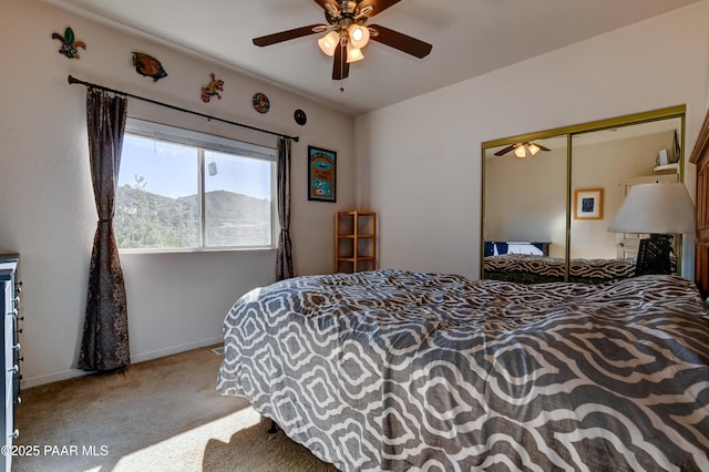 bedroom with a closet, light carpet, a mountain view, ceiling fan, and baseboards