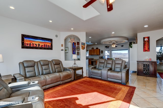 living area with arched walkways, ceiling fan, light tile patterned floors, and recessed lighting