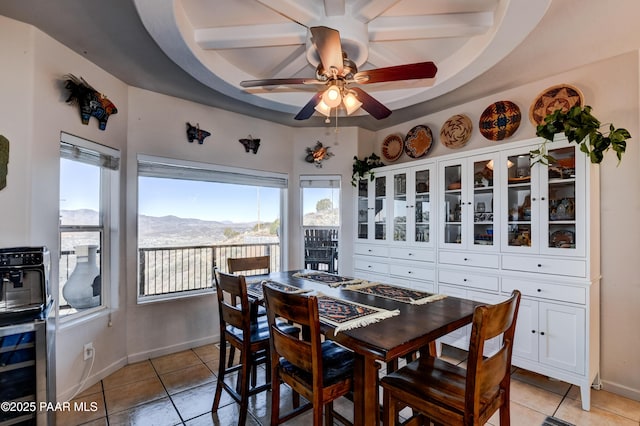 dining space with light tile patterned floors, baseboards, ceiling fan, wine cooler, and a mountain view