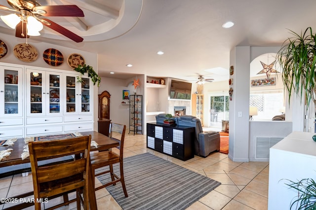 dining space with a tiled fireplace, ceiling fan, light tile patterned flooring, and visible vents