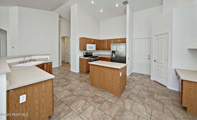 7461 N Windy Walk Way, Prescott Valley, AZ 86315 - kitchen with stainless steel appliances, high vaulted ceiling, arched walkways, a center island, and brown cabinets