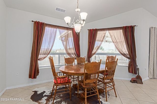 dining space featuring a notable chandelier, light tile patterned floors, and vaulted ceiling