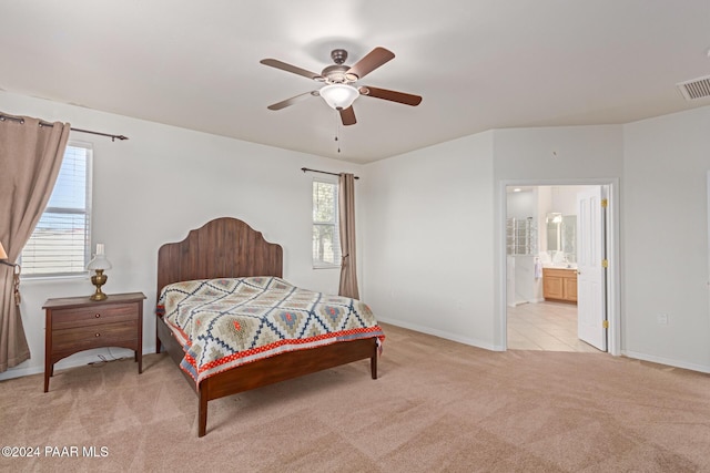 bedroom with ceiling fan, light colored carpet, and connected bathroom