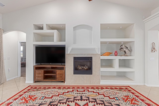 tiled living room featuring a tile fireplace, built in features, and high vaulted ceiling