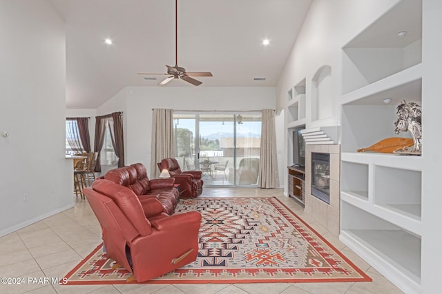 living room featuring ceiling fan, high vaulted ceiling, built in features, a tiled fireplace, and light tile patterned flooring